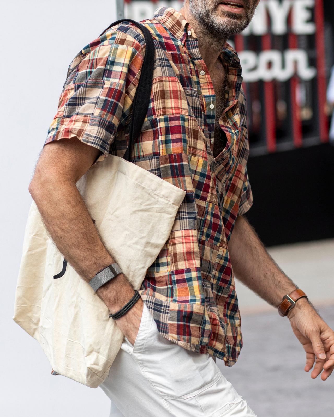 A man dressed in a short-sleeve plaid shirt and light-colored pants