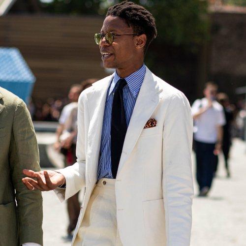 Mannequin portant un costume blanc, une chemise bleue à rayures, une cravate foncée et une pochette de costume à Pitti Uomo