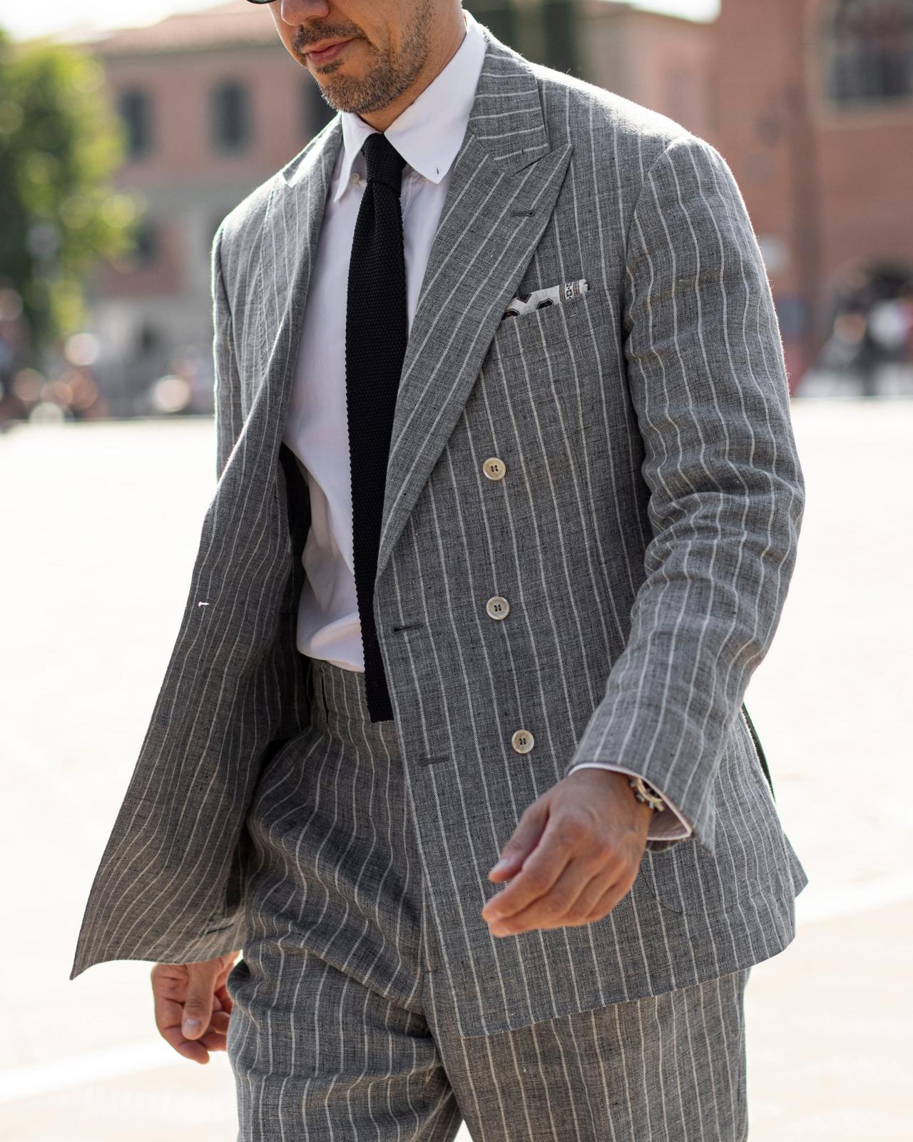 A man wearing a grey pinstripe double-breasted suit paired with a white dress shirt and a black tie