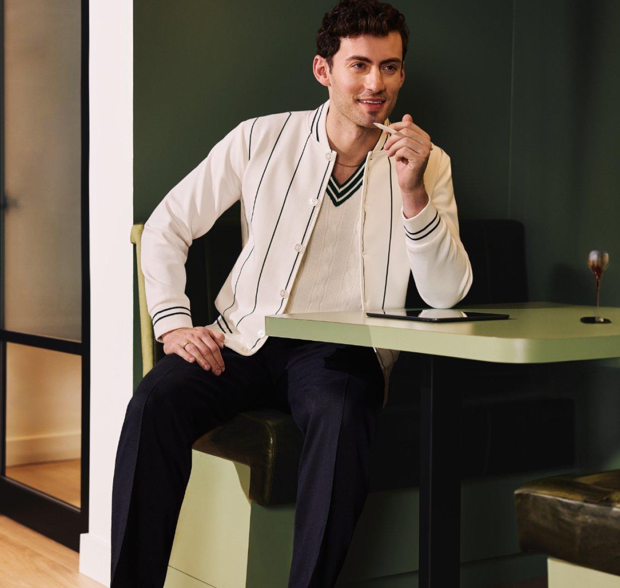 A man wearing an overshirt with off-white sweater and black pants