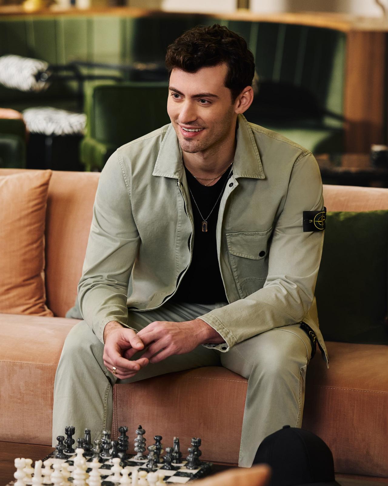 A man wearing an olive overshirt and pants with black t-shirt