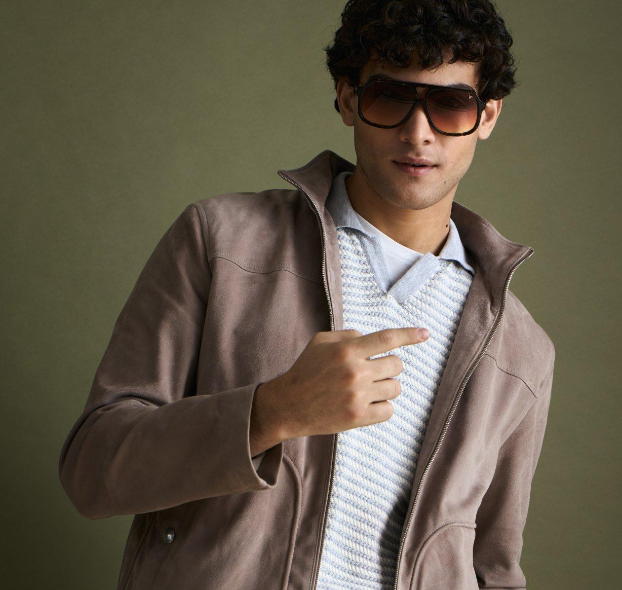 A man with brown-grey overshirt, knit t-shirt and dark grey pants