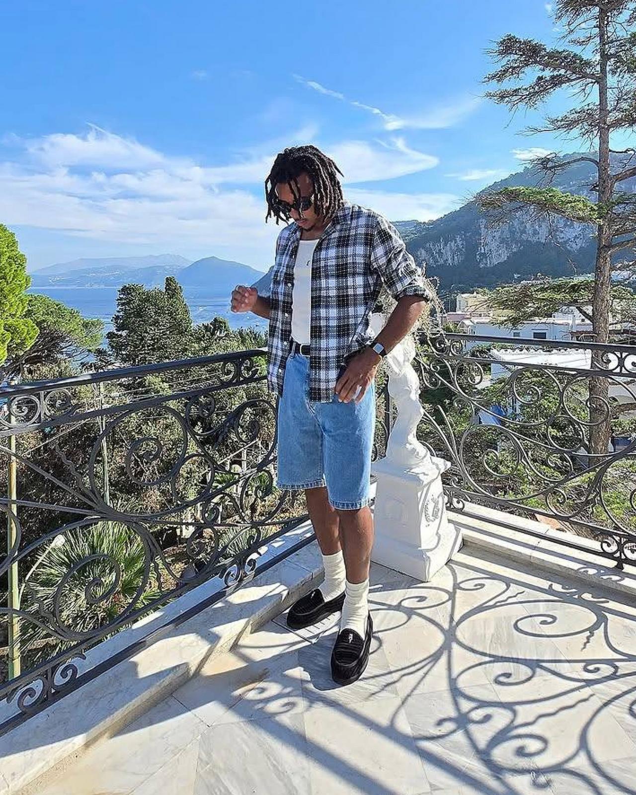 Jules wearing a check patterned shirt with denim shorts and black loafers