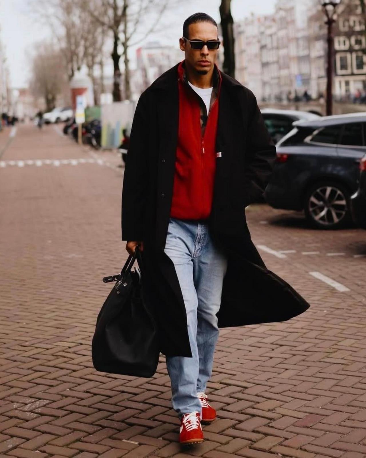 Virgil wearing black coat, red sweater and slim sole sneakers