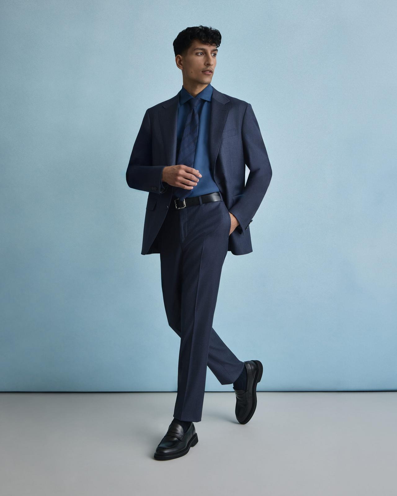 Un homme portant un costume bleu marine avec une chemise bleue et une cravate bleu foncé