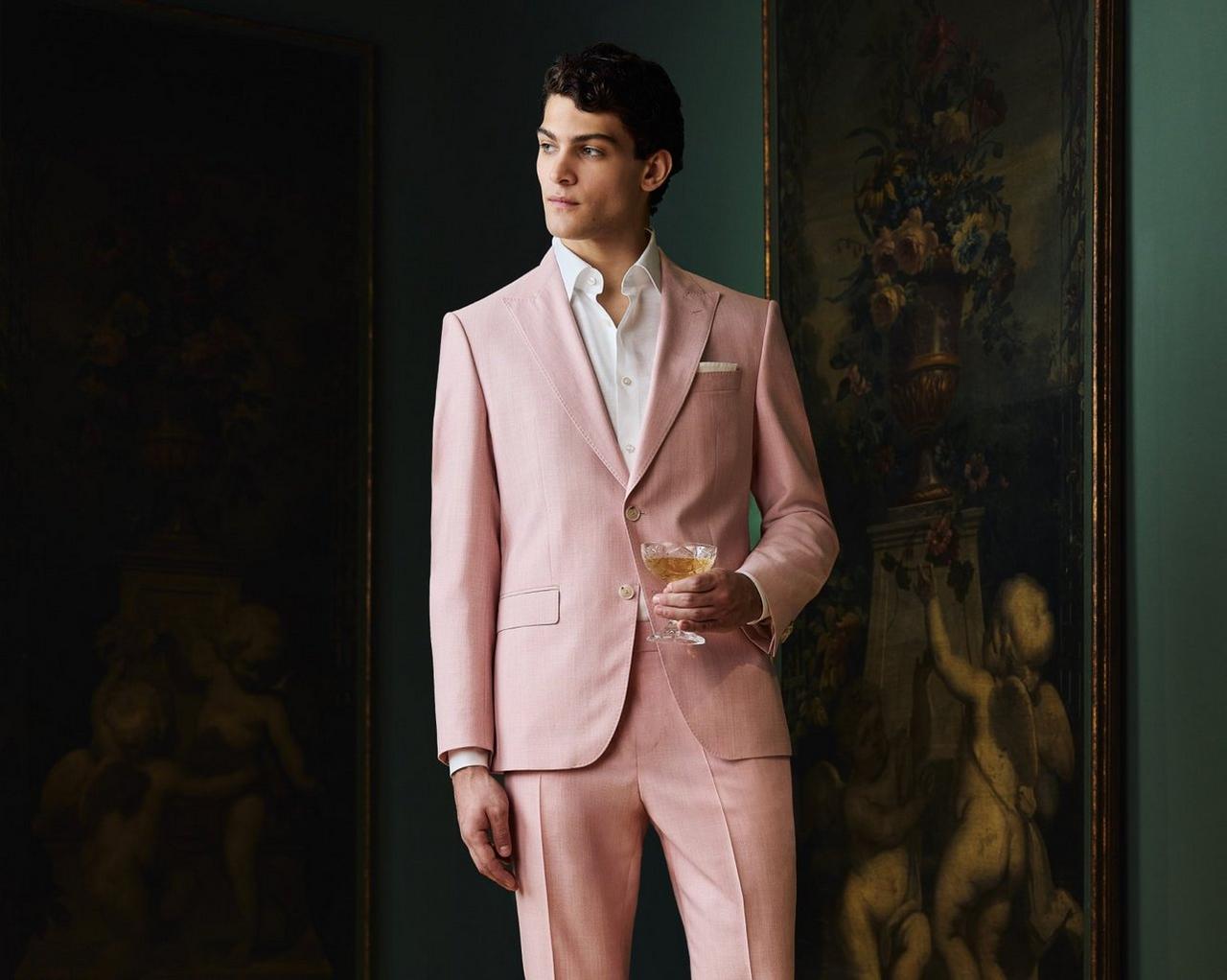 A man wearing a pink suit with white shirt and white pocket square