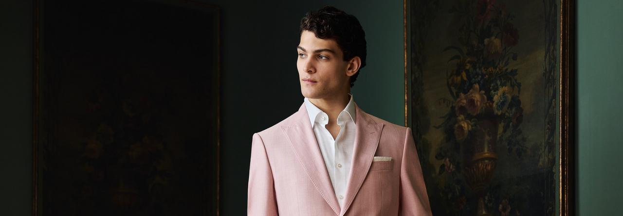 Un homme portant un costume rose avec une chemise blanche et une pochette de costume blanche