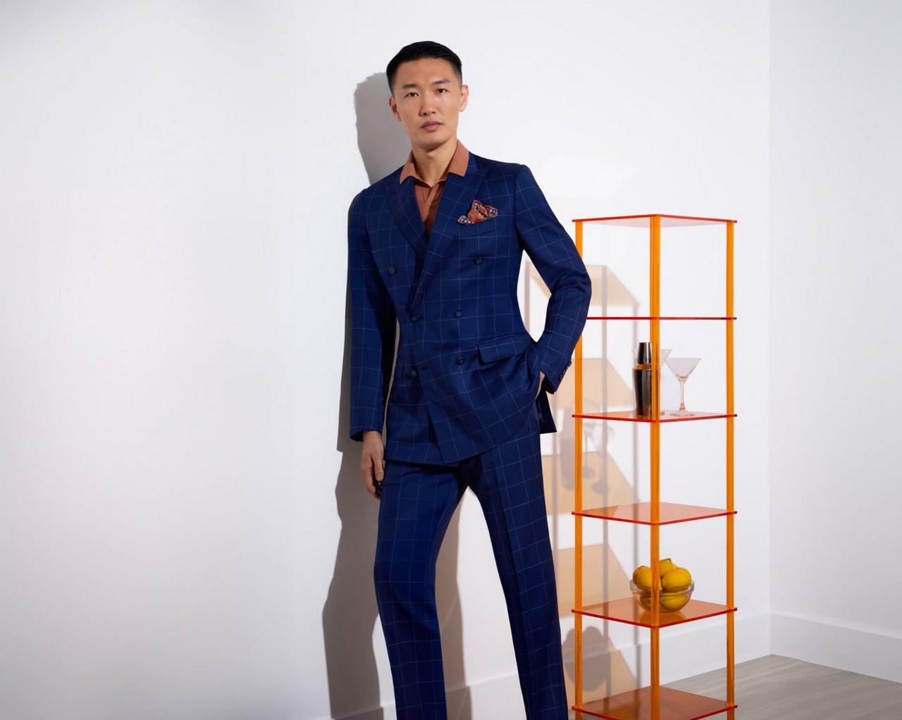 Un homme portant un costume bleu très foncé avec une chemise de couleur rouille et une pochette de costume imprimée de couleur rouille