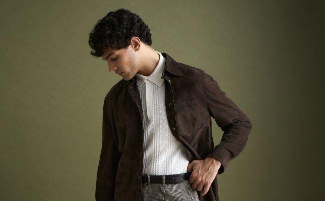 A man wearing a dark chocolate overshirt, polo t-shirt and grey check pants