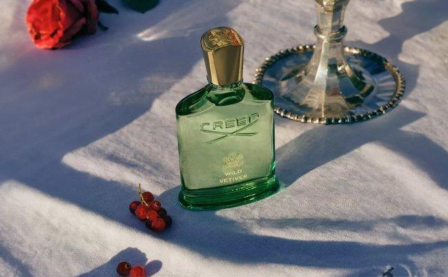 Un flacon d’eau de Cologne Creed Aventus exposé sur une plateforme blanche avec un éclairage dramatique