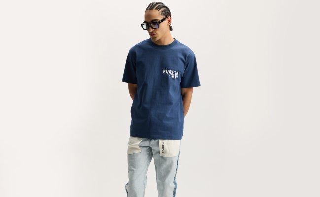 A person wearing a navy blue Rusty Dead Ringer T-Shirt paired with light blue jeans