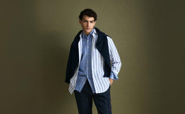A man wearing a Navy Blue vest with white and blue striped pattern shirt