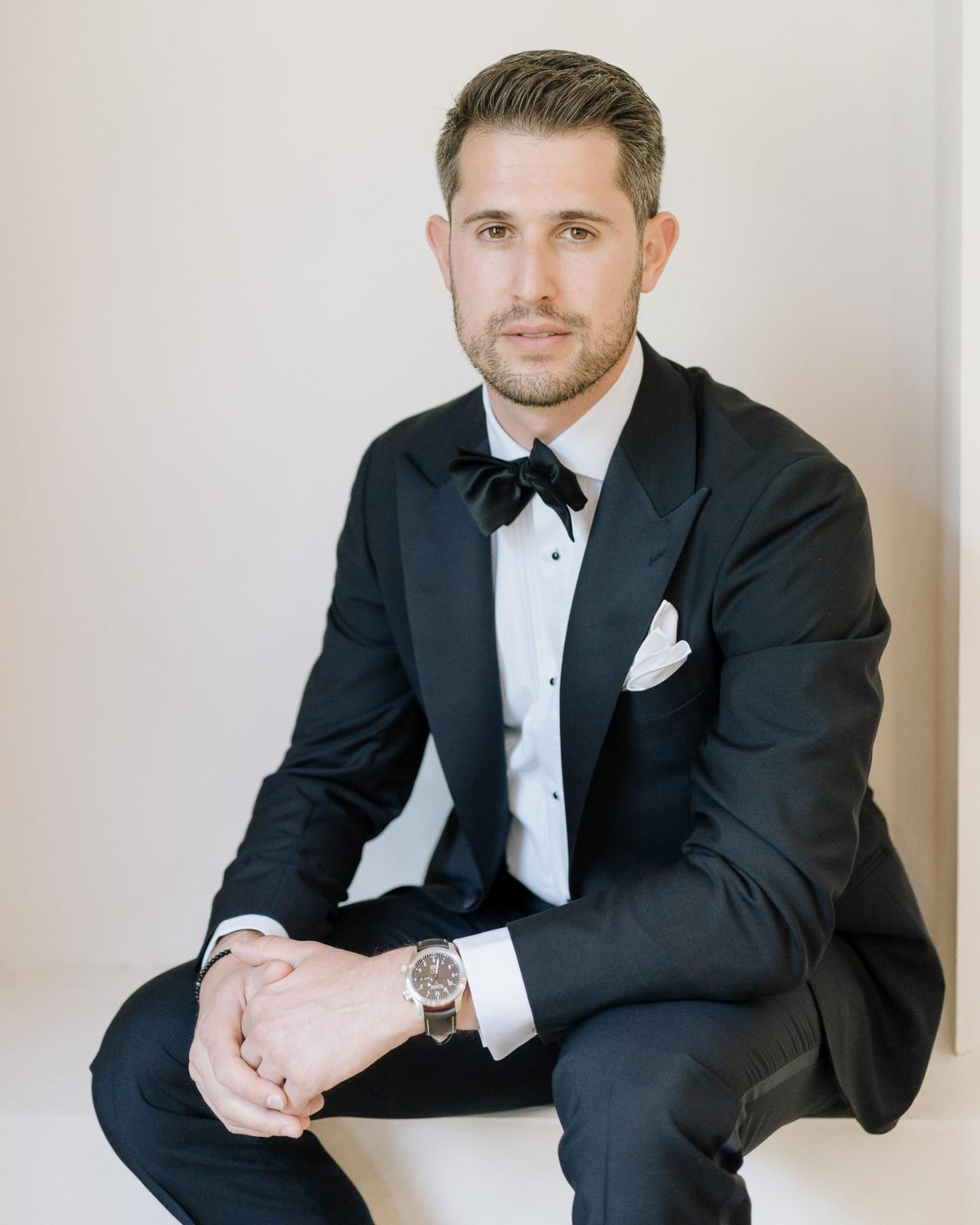 Un homme vêtu d’un smoking noir classique avec une chemise habillée blanche, un nœud papillon noir et une pochette de costume