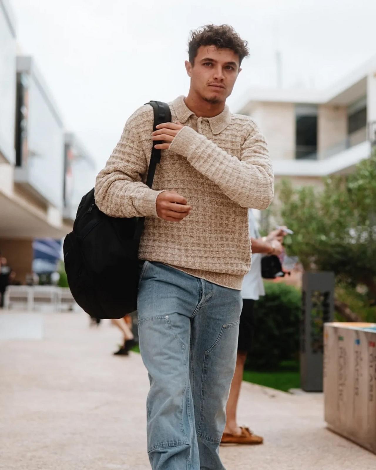 Lando Norris wearing a beige color knit polo sweater and light blue denim jeans