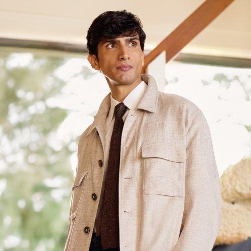 Un homme portant une surchemise beige avec une cravate brun foncé et une chemise blanche