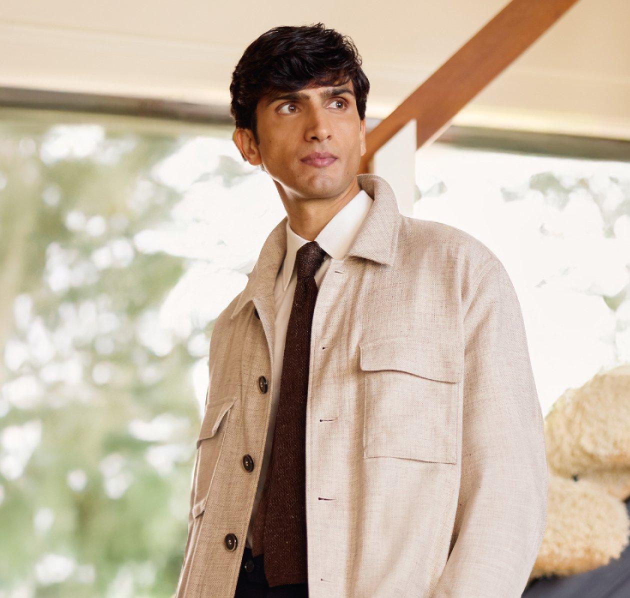 Un homme portant une surchemise beige avec une cravate brun foncé et une chemise blanche