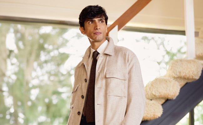 A man wearing a beige overshirt with dark brown tie and white shirt