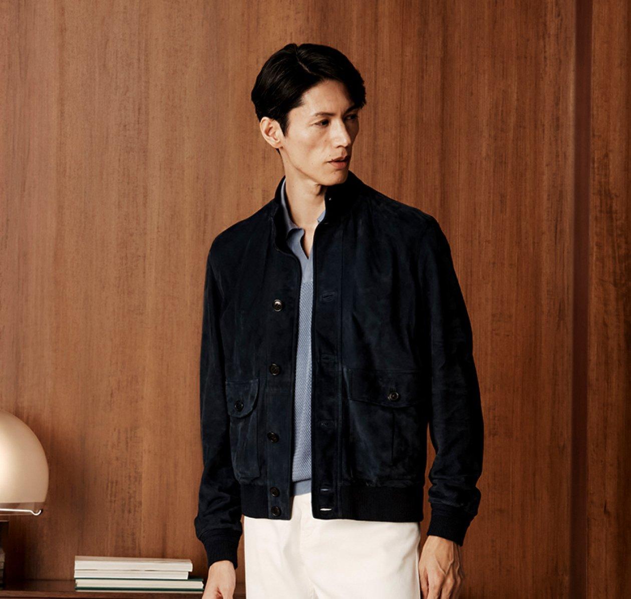 A man wearing a dark blue overshirt with blue-gray t-shirt and off-white pants