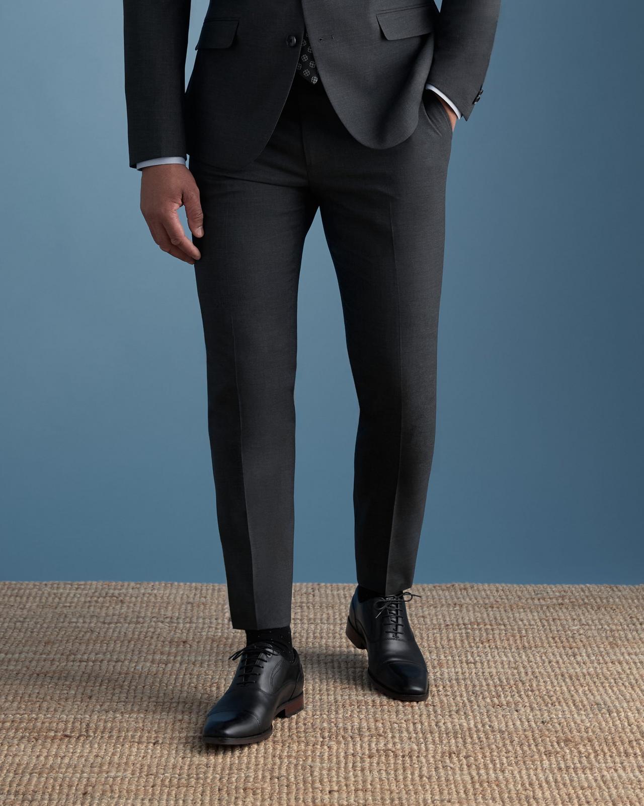 Modèle portant un costume gris anthracite foncé, associé à des chaussures habillées noires