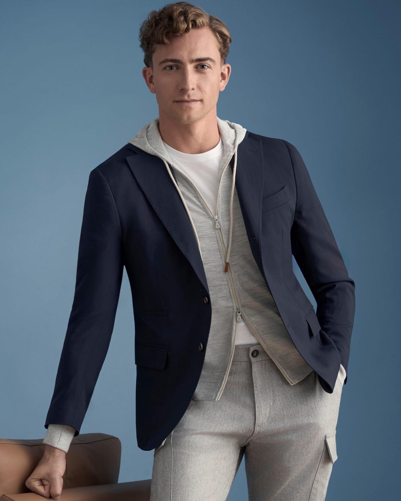 Modèle portant un blazer superposé à un sweat à capuche zippé gris clair et un pantalon assorti