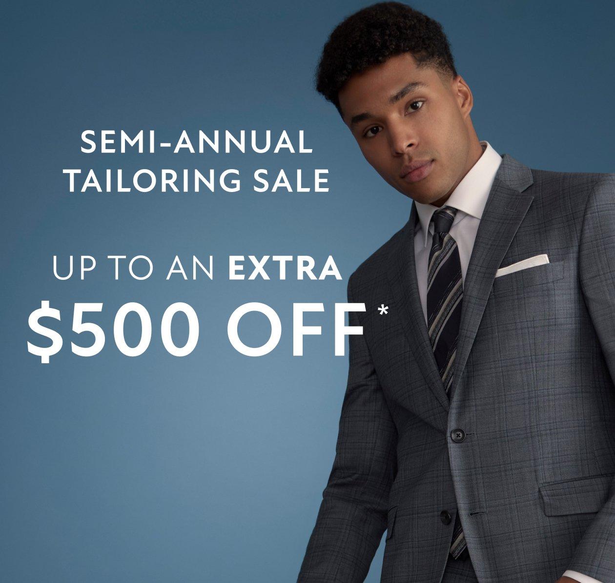 A man wearing a suit with white shirt, black and grey tie.