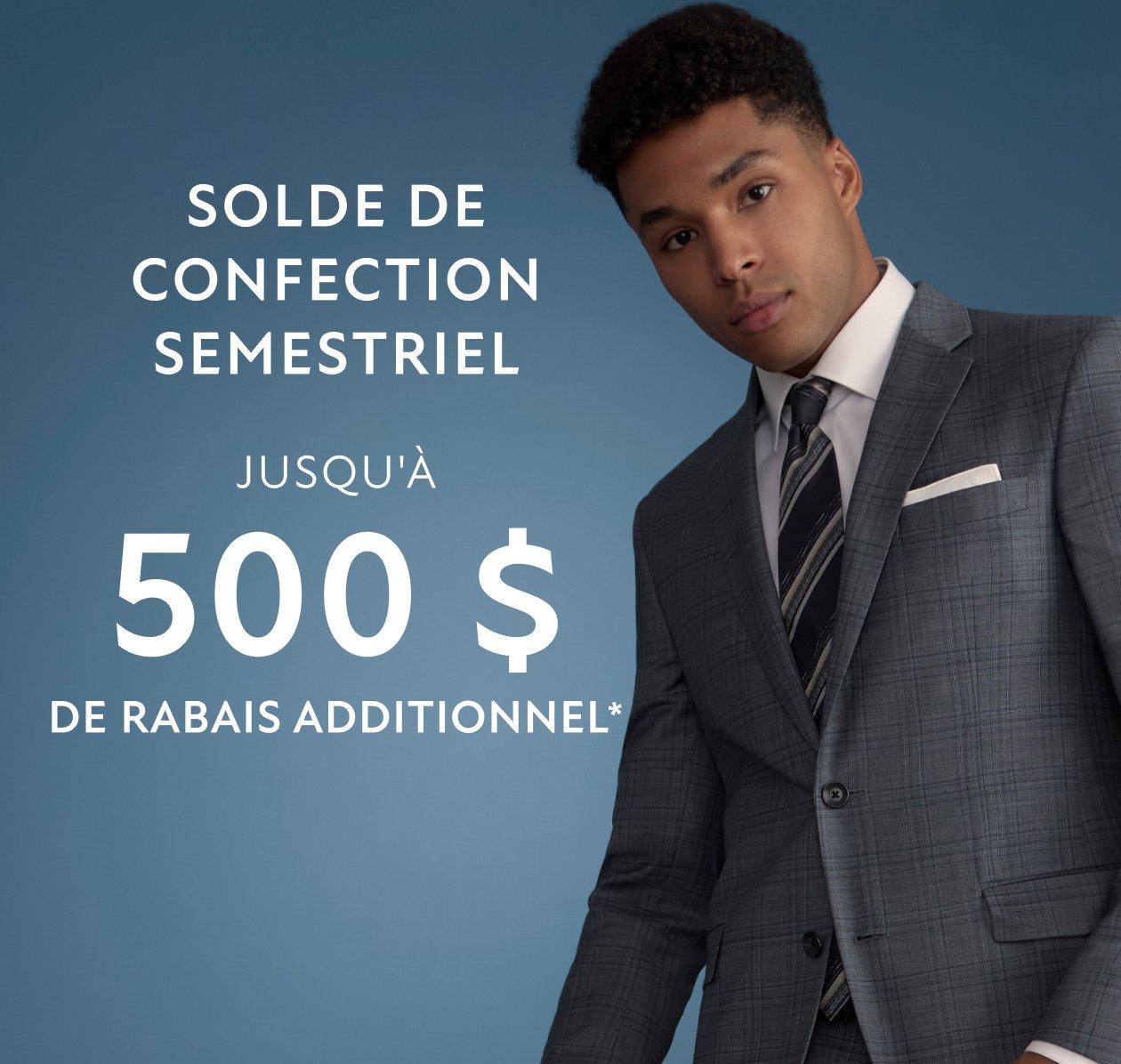 Un homme portant un complet, avec une chemise blanche et une cravate noire et grise.