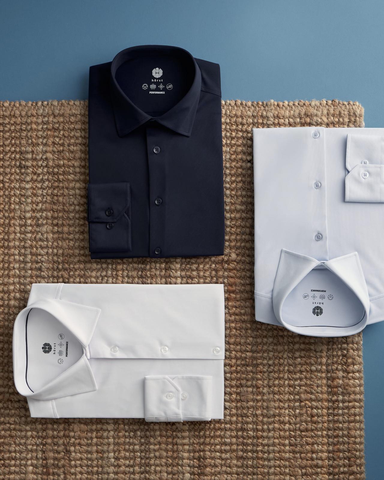 neatly folded men's dress shirts in black, white, and a light blue shade