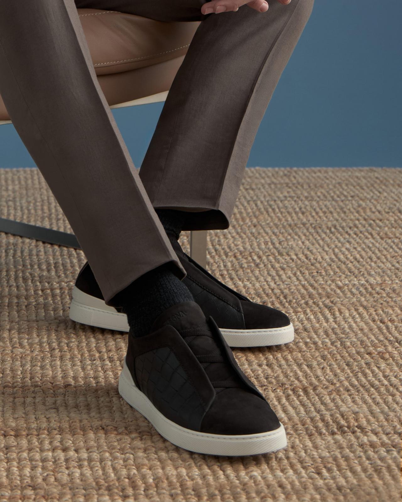 Mannequin portant un pantalon marron foncé et des baskets noires en daim à enfiler