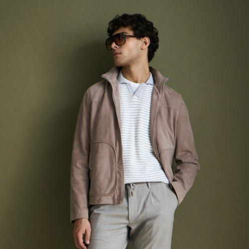 Un homme portant une surchemise couleur argile, un polo argent froid, des lunettes de soleil brun foncé et un pantalon gris