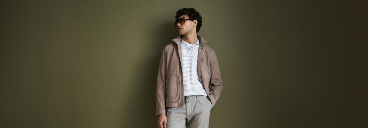 Un homme portant une surchemise couleur argile, un polo argent froid, des lunettes de soleil brun foncé et un pantalon gris