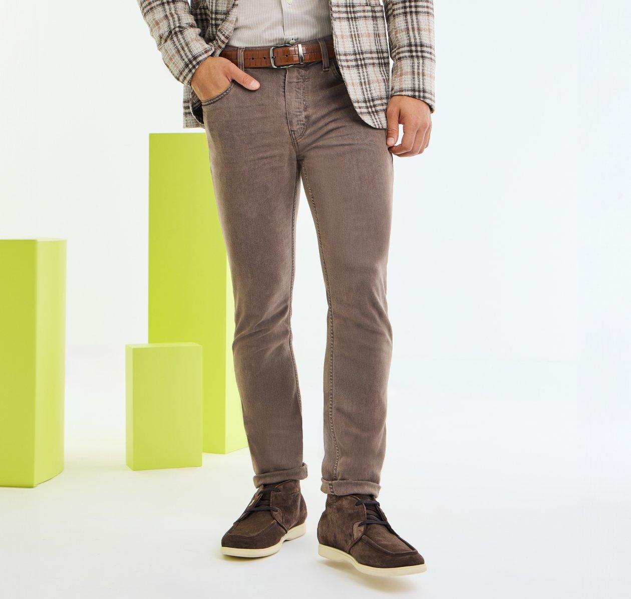 A close-up of a model wearing brown Paige jeans