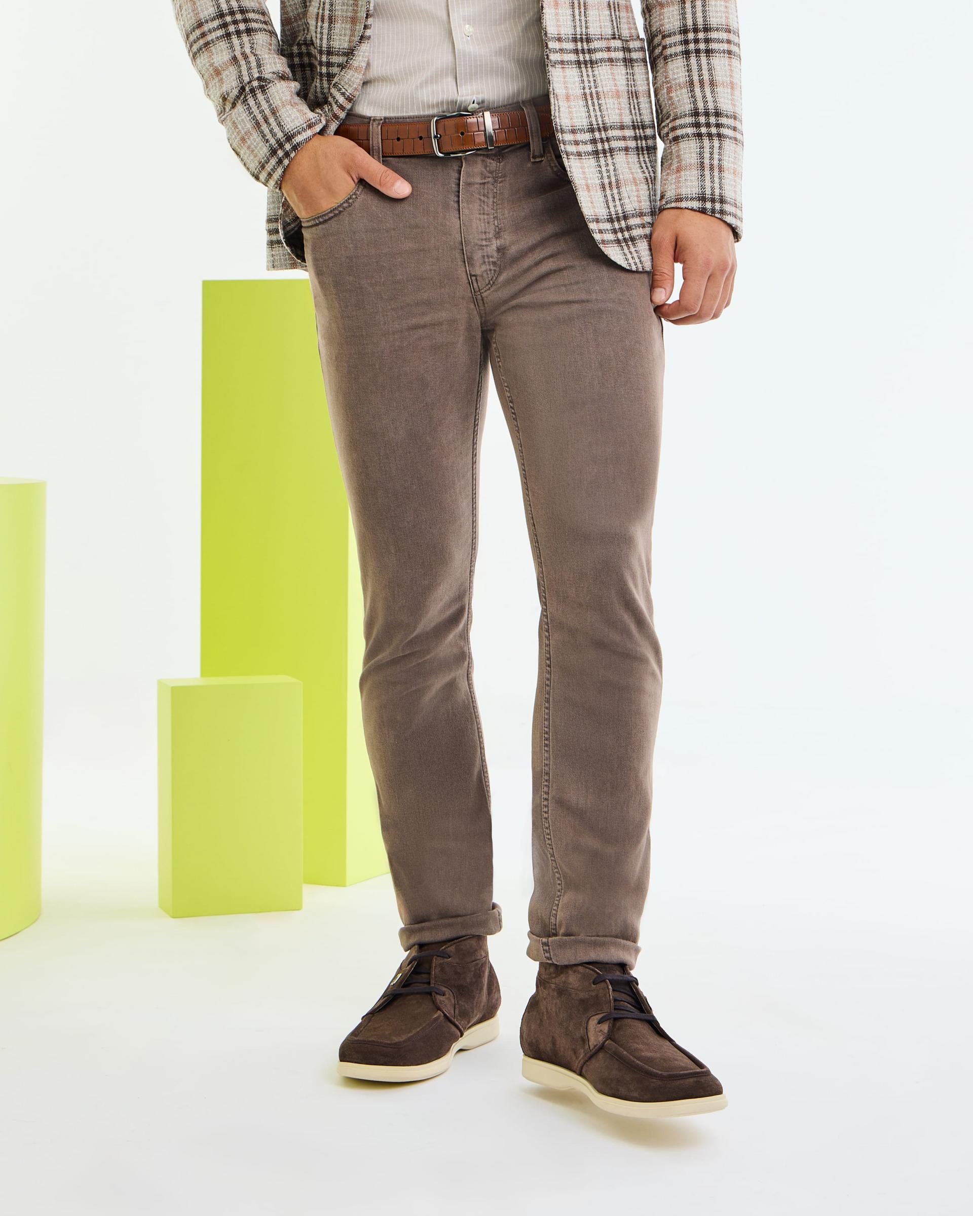 A close-up of a model wearing brown Paige jeans