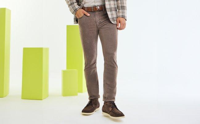 A close-up of a model wearing brown Paige jeans