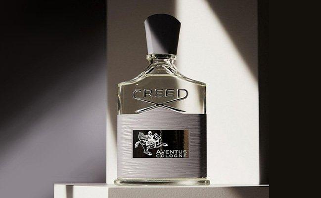 A bottle of Creed Aventus cologne displayed on a white platform with dramatic lighting