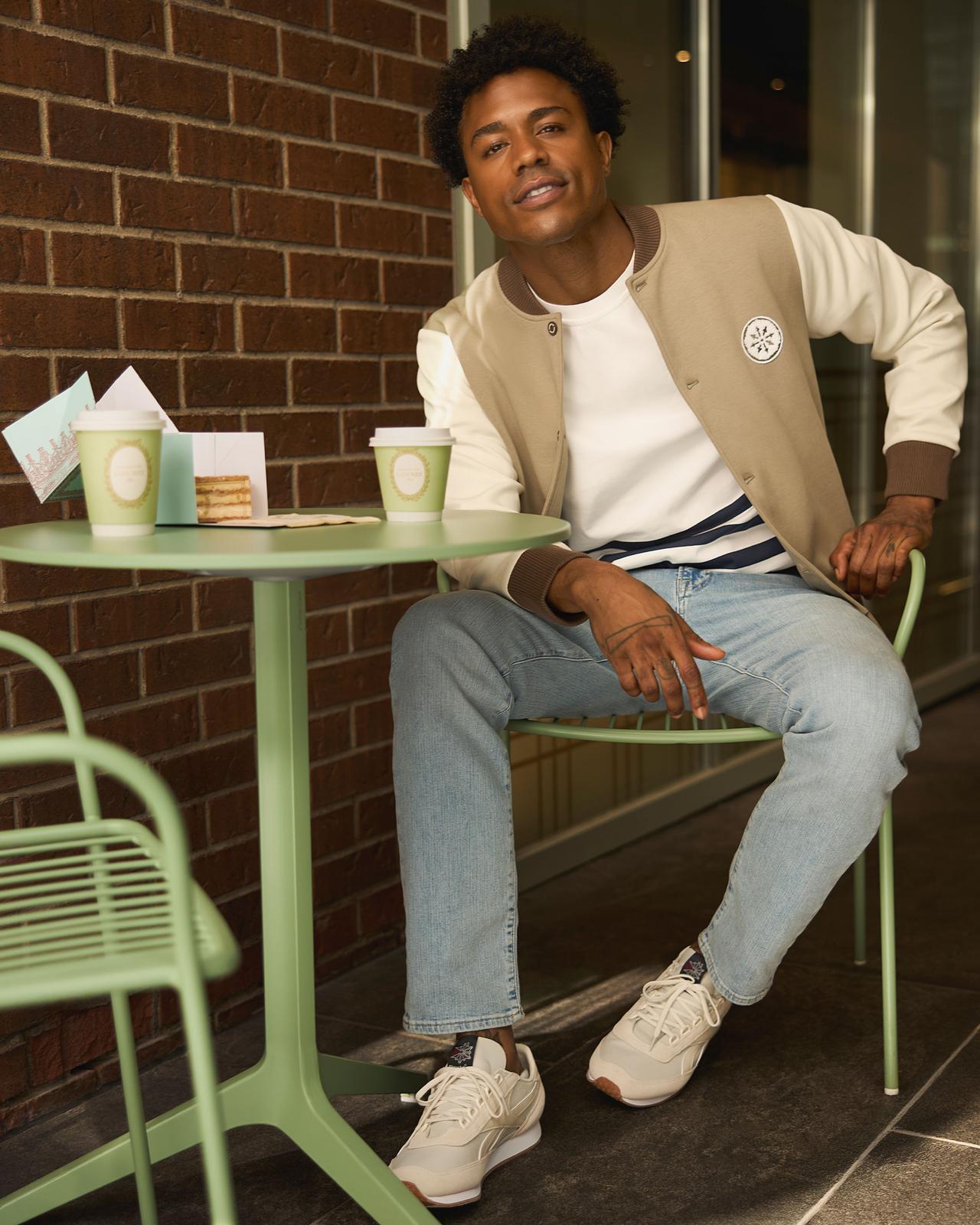 Homme portant une veste blanche et beige avec un jean bleu pâle