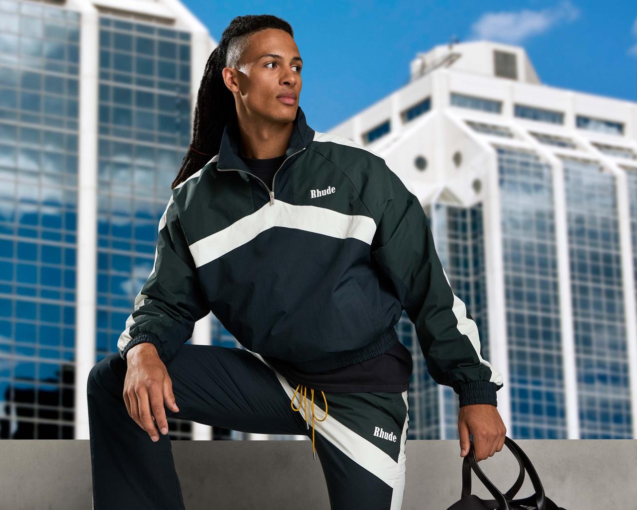 male wearing athletic wear by Rhude with city in background