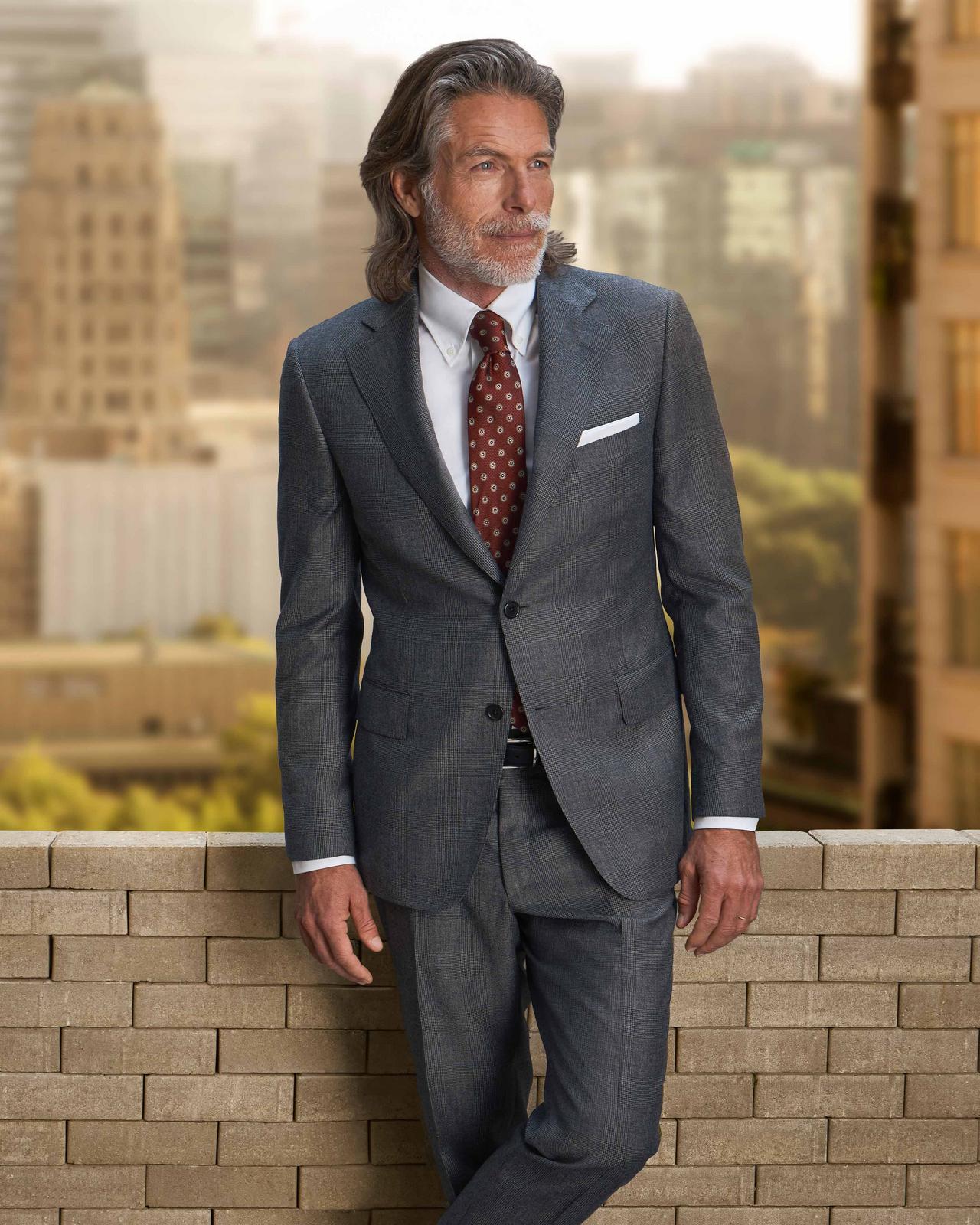 man wearing a grey suit with buildings in background