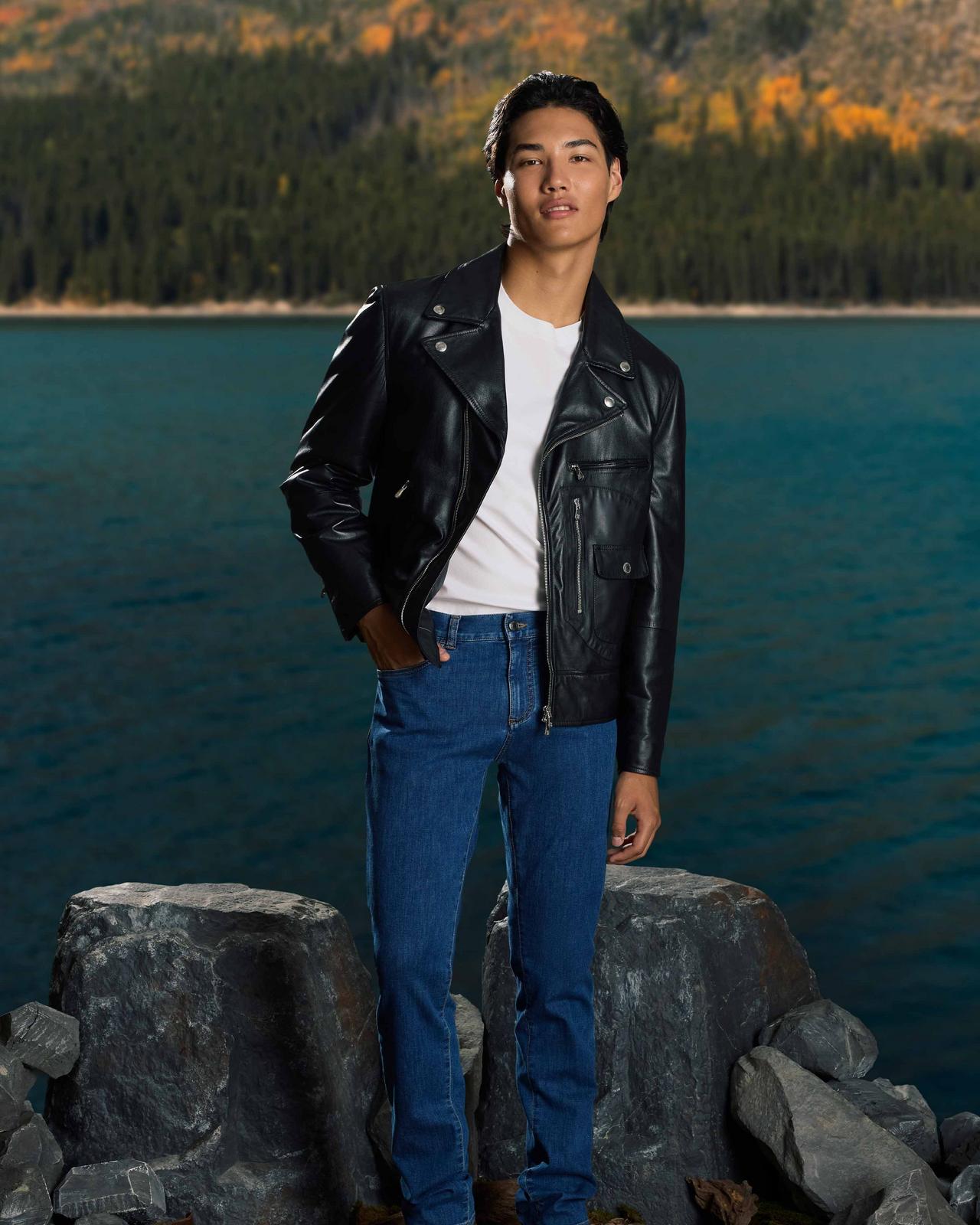 man wearing a leather jacket with lake in background