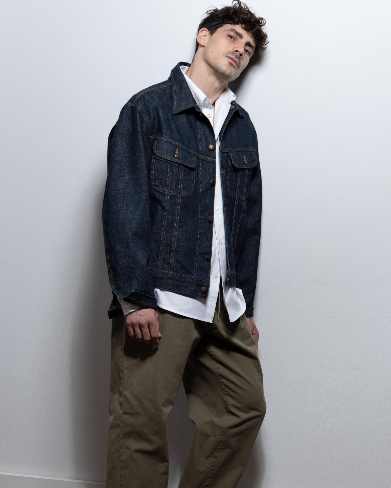 Paul Poirier posing wearing jean jacket, dress shirt and pants