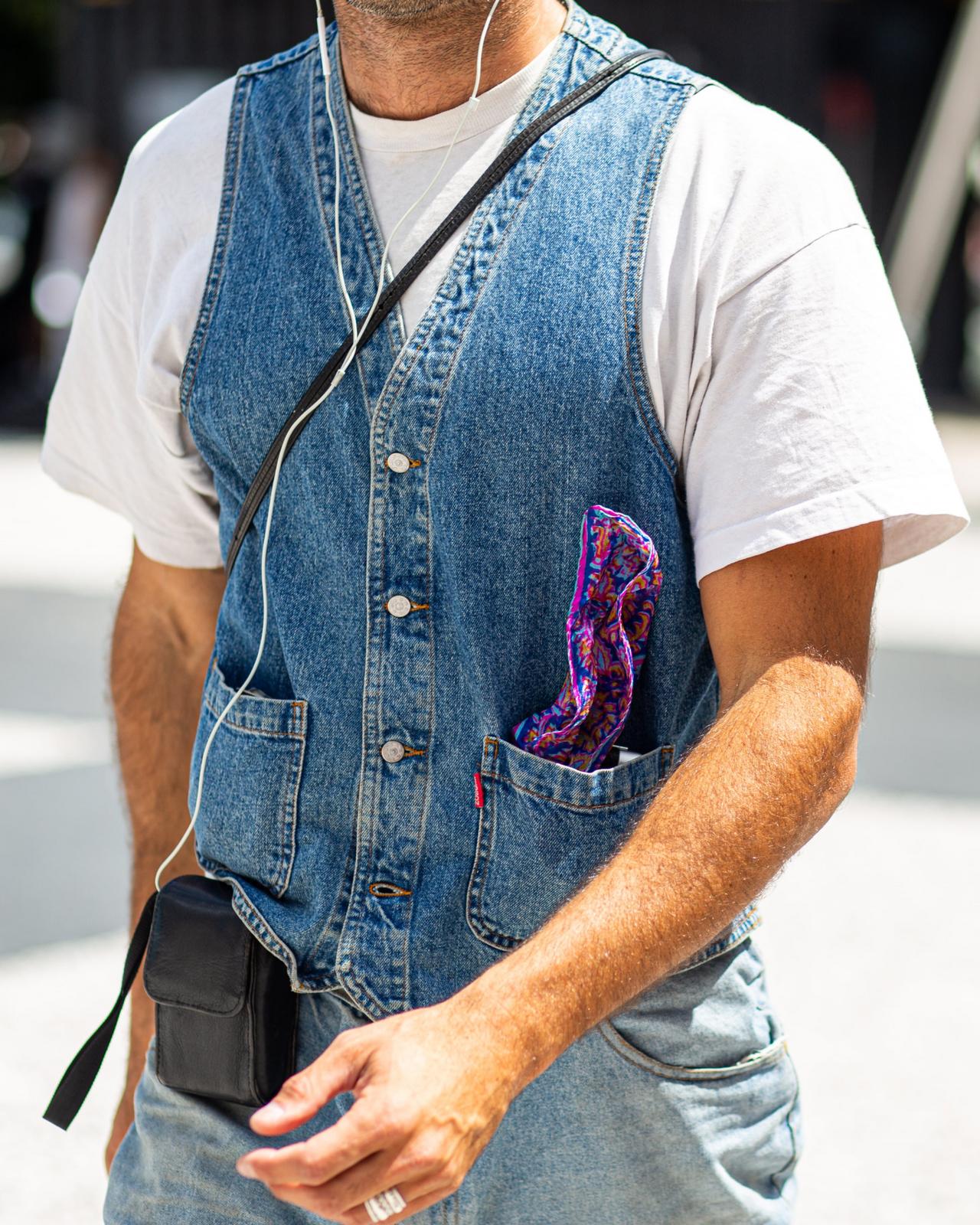 Man in blue denim vest layered over white t-shirt and jeans for a casual, comfortable look