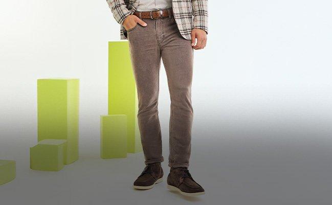 Man wearing brown Paige pants with a plaid blazer and leather belt