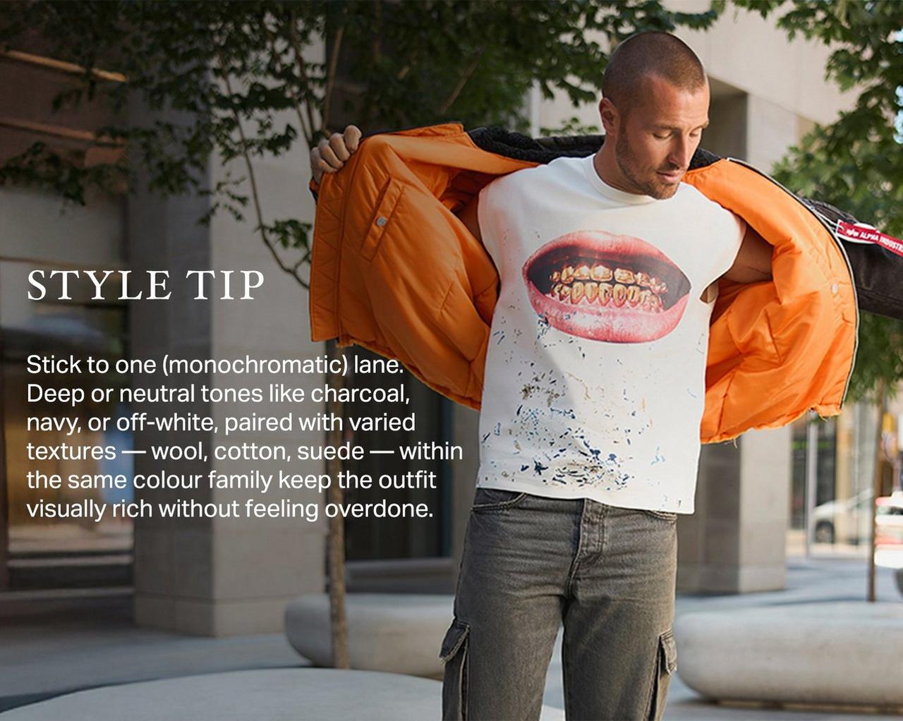 Man wearing an orange jacket layered over a graphic T-shirt