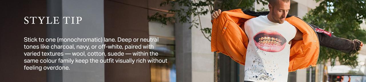 Man wearing an orange jacket layered over a graphic T-shirt