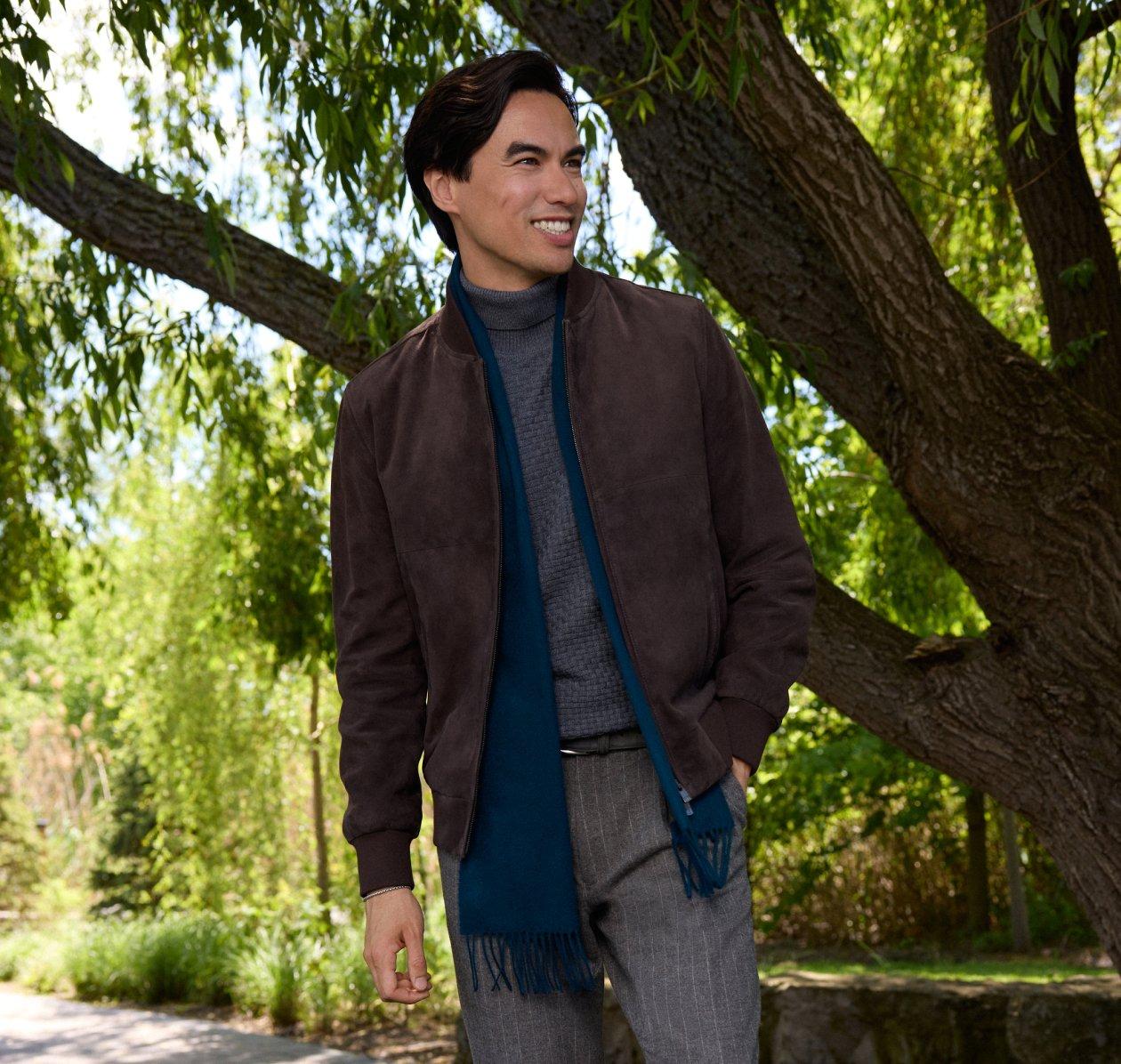 Homme portant un blouson bombardier en suède brun, un col roulé gris et une écharpe sarcelle à franges à l'extérieur, LW Outerwear, collection A/H26