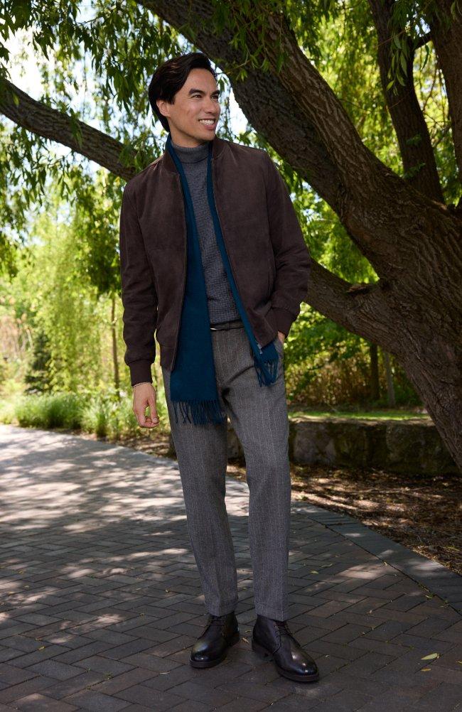 Man wearing a brown suede bomber jacket, grey turtleneck, and teal fringed scarf outdoors, LW Outerwear, FW26 collection