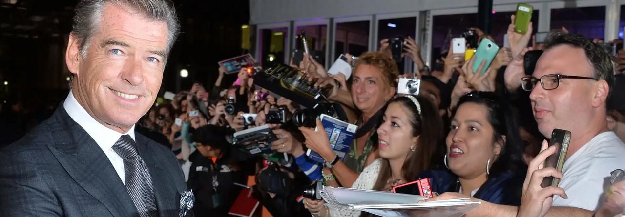 L’acteur, vêtu d’un complet foncé à carreaux et d’une cravate, échange chaleureusement avec ses admirateurs alors qu’ils prennent des photos et lui demandent des autographes