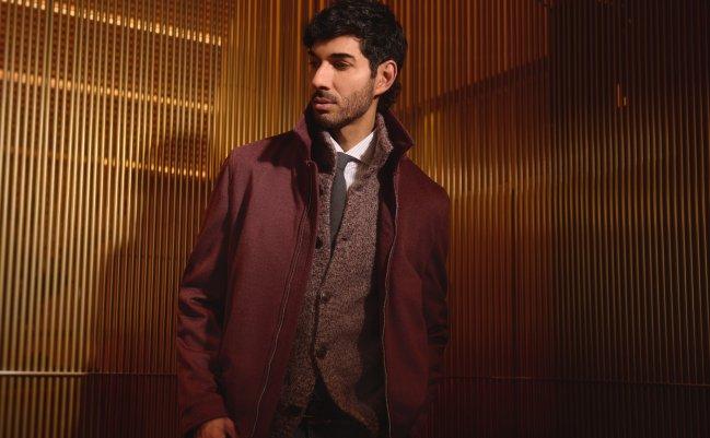 Mannequin portant un caban marron bordeaux superposé à un pull texturé et une cravate