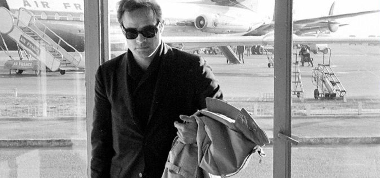 A man in sunglasses and jacket walking through an airport