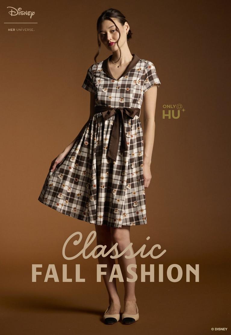 Model wearing Disney Her Universe plaid dress with brown collar and waist bow, holding skirt hem. Shop now.