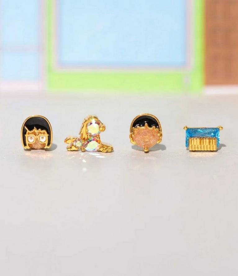 Four mismatched stud earrings, including a character face, unicorn, head silhouette, and blue gem. Shop jewelry.